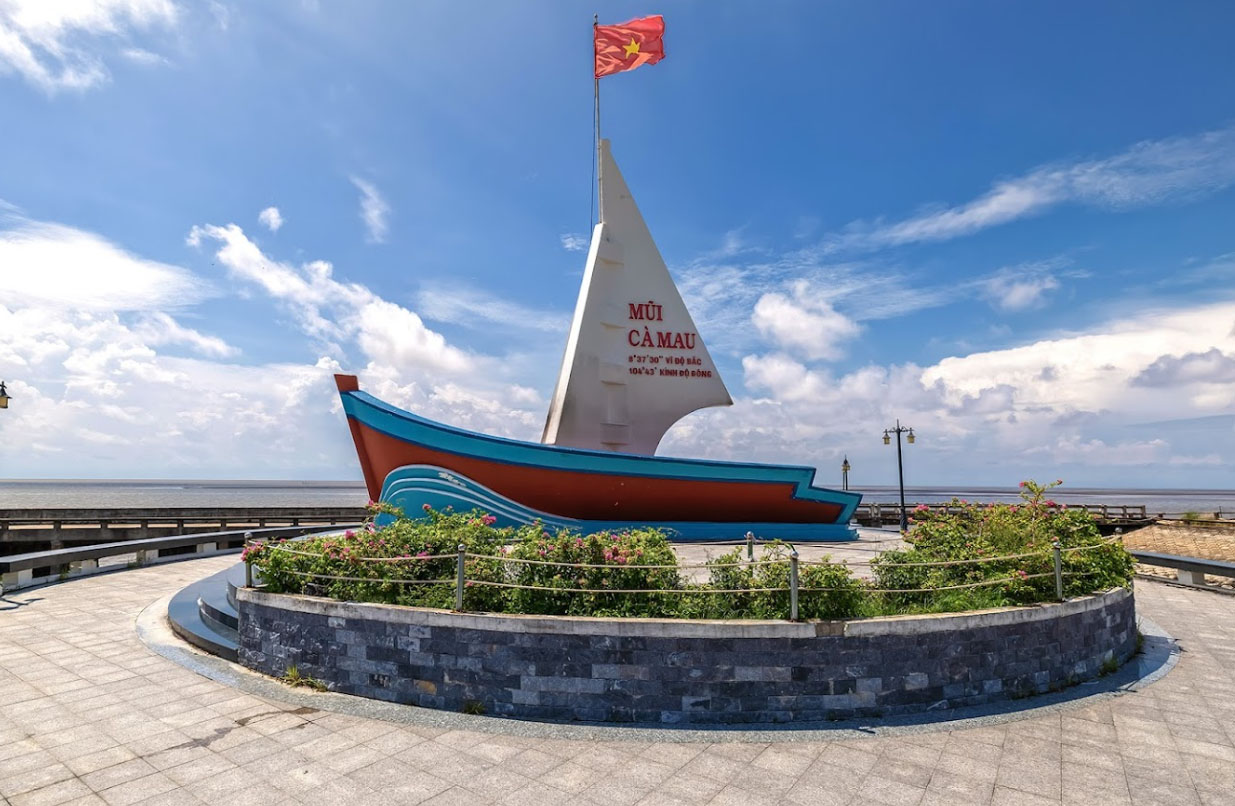 Cầu gỗ hoặc cầu ván bắc qua mặt nước trong rừng ngập mặn Cà Mau, với cây xanh rậm rạp hai bên.